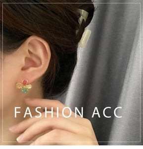 Close-up of a floral stud earring with colorful pear-shaped beads on a model's ear