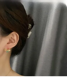 Detail of vintage floral earrings with colorful stones on model against gray background
