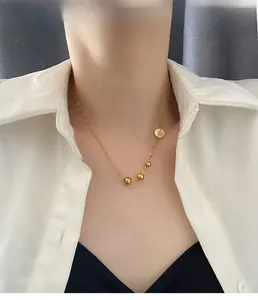 Asymmetrical gold beaded titanium steel necklace shown on a model neck with a white shirt