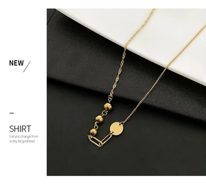 Detail view of gold titanium necklace featuring asymmetric ball and rectangle charms