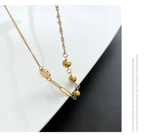 Macro view of gold asymmetric chain necklace featuring round metal beads and long oval links