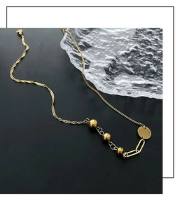 Close-up of golden sphere beads and wavy texture link chain on minimalist necklace