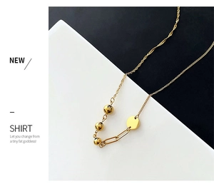 Detailed shot of asymmetric gold necklace featuring polished beads and geometric flat disc