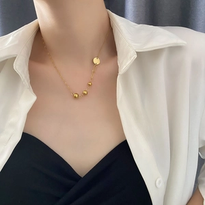Minimalist gold titanium necklace with asymmetric beads and geometric pendant on model
