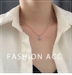 Détail du pendentif Fu argenté sur collier de perles roses porté par un mannequin