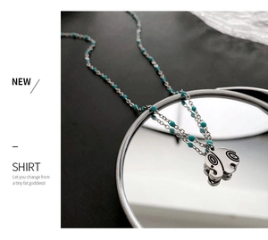 Detail of silver elephant pendant with turquoise beads on a reflective mirror base