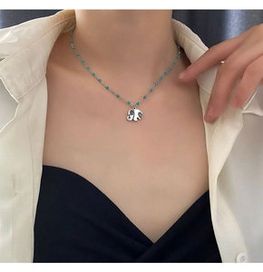 Detail of silver elephant pendant necklace with blue beads worn by a model