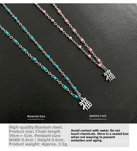 Détail du collier pendentif Fu en acier titane avec perles roses et bleues sur chaîne
