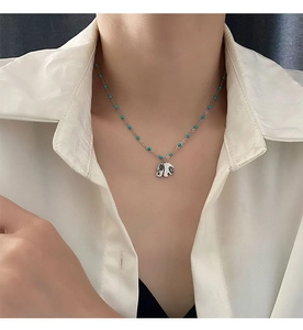 Detail of elephant pendant necklace with turquoise beads on a minimalist steel chain