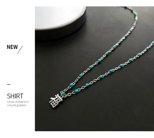 Détail macro du collier en perles bleu ciel et acier titane avec pendentif chinois Fu