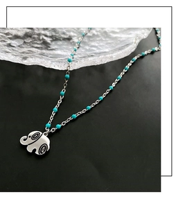 Close-up of elephant pendant with turquoise beads on a minimalist silver chain