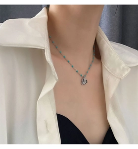 Detail of a minimalist silver butterfly pendant necklace with turquoise beads on a model