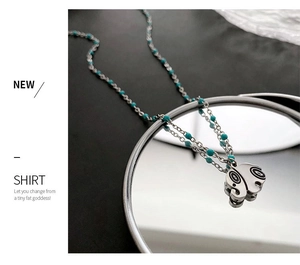 Detailed shot of an elephant pendant with blue beads on a reflective mirror surface