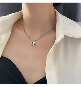 Close-up of elephant pendant necklace with turquoise beads on a silver chain worn by model