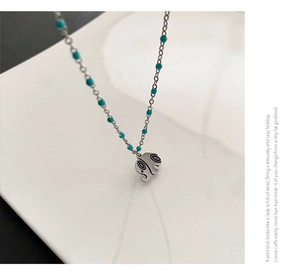 Detailed macro view of bohemian silver chain with turquoise beads and spiral elephant pendant