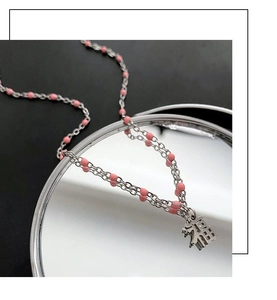 Vue détaillée du collier en argent avec perles roses et pendentif Fu sur miroir
