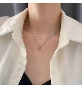 Détail d'un collier en acier titane avec perles turquoise et pendentif symbole Fu