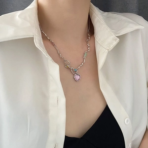 Detail of silver wavy chain necklace with pink heart pendant and colorful stones