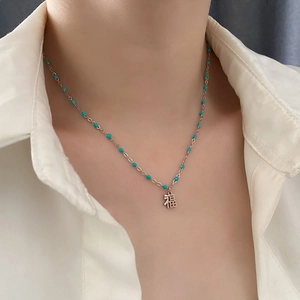 Collier élégant perlé de pierres turquoise et pendentif Fu porté au cou