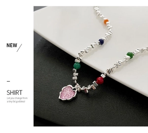Détail d'un collier de perles colorées avec pendentif cœur rose et maillons argentés