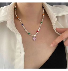Détail du collier de perles colorées avec pendentif cœur rose scintillant sur modèle