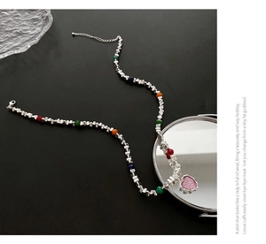 Détail d'un collier pendentif cœur coloré avec cubes argentés sur une surface noire