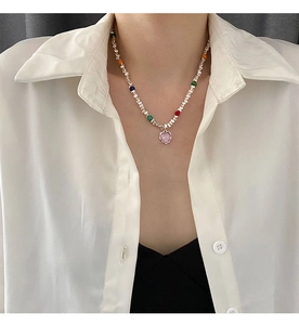 Détail d'un collier de perles colorées avec pendentif cœur rose sur un mannequin
