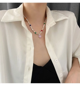 Détail du collier pendentif cœur rose avec perles colorées porté par un mannequin en chemise