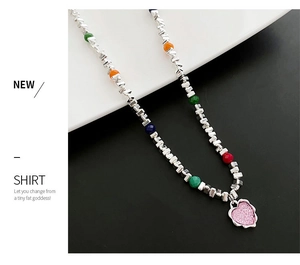 Détail du collier de perles avec cubes argentés, perles colorées et pendentif cœur rose