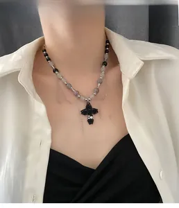 Détail du pendentif croix rose gothique avec perles sombres et accents en métal