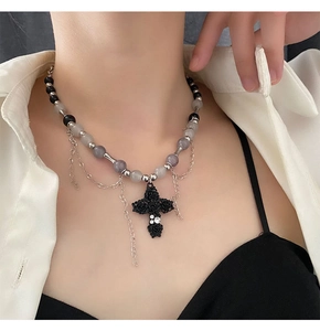 Détail du pendentif croix gothique avec relief rose et collier en perles grises