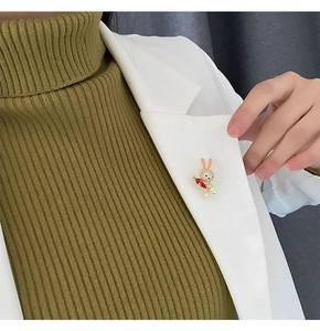 Close-up of a cute rabbit brooch with crystals on a white blazer lapel with carrot detail