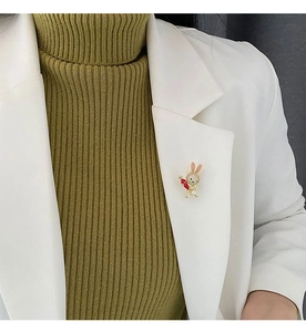 Detail of cute rabbit brooch with white zircons and carrot on a white suit lapel