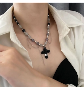Détail du collier à perles avec pendentif croix rose et chaînes multicouches