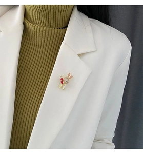 Close-up of a cute rabbit brooch with white zircons and pink ears on a beige blazer
