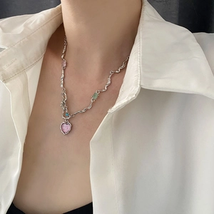 Silver wavy necklace with pink heart pendant and colorful stones worn by a model
