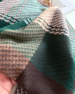 Primo piano del tessuto a maglia a quadri spessi con nappe e morbida trama in finto cashmere