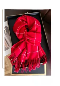 Close-up of red plaid cashmere scarf with soft tassel details on a display tray