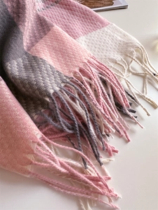 Dettaglio della trama in maglia e frange sulla sciarpa a quadri rosa e grigio morbida