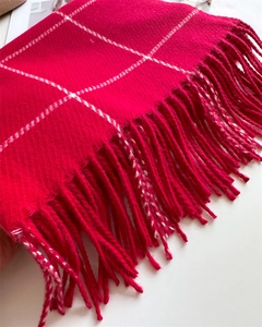 Detailed view of red plaid scarf with fine knitting texture and long tassel edges