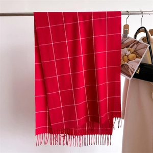 Detail of red and white checkered knit scarf featuring elegant fringe tassels for winter