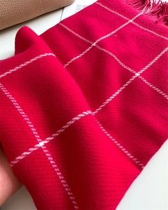 Detail of red checkered scarf with soft cashmere texture and elegant fringe edges