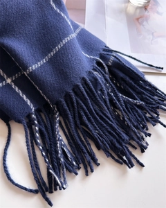 Detail of navy blue plaid scarf showing soft cashmere-like texture and tassel fringe