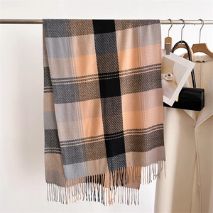Dettaglio di una morbida sciarpa a quadri con frange e motivo color block grigio e arancio