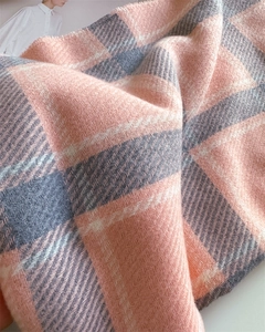 Nahaufnahme eines rosa-grau karierten Schals mit Köperbindung und feinen Fransenkanten