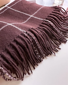 Macro detail of wine red plaid scarf with classic tassels and soft cashmere-like texture