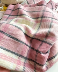 Close-up of pink and grey plaid scarf showing twill weave texture and soft tassels