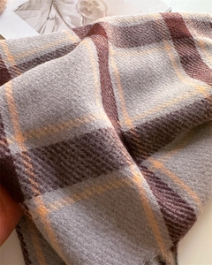 Detailaufnahme von weichem Plaid-Kaschmir-Schal mit klassischen grauen und orangefarbenen Fransen