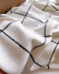 Detailed close-up of monochrome herringbone plaid fabric with a soft cashmere-like texture