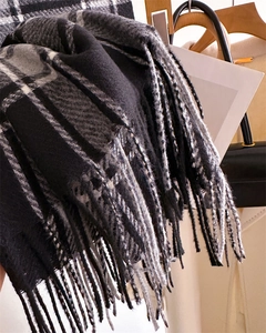 Detail eines dicken karierten Winterschals mit schwarz-grau-weißen Fransen am Bügel